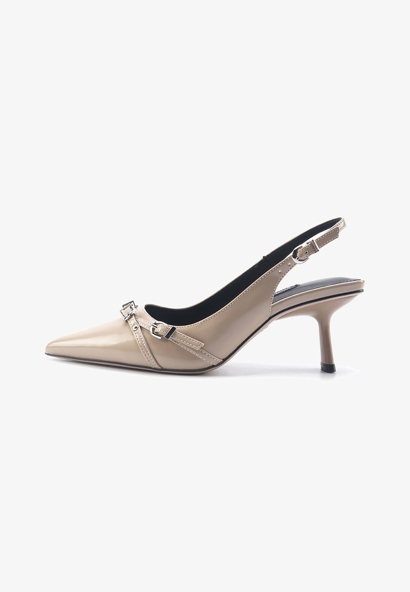 Beige patent leather slingback heels with a pointed toe, ankle strap with buckle detail, and a slim high heel. Smooth texture, minimal design.