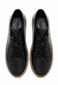 Sneaker nere in pelle con punta rotonda, lacci neri e suole in gomma marrone. Design strutturato all'interno della scarpa con dettagli di cucitura sottili.
