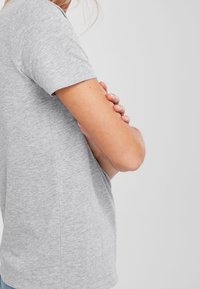 Szara bawełniana koszulka z krótkim rękawem, okrągłym dekoltem i luźnym krojem. Prezentuje gładką fakturę z minimalną ilością szwów i bez wzorów.