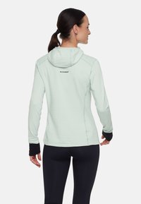 Felpa con cappuccio a maniche lunghe di colore verde menta chiaro, con design aderente, texture a righe e cappuccio. Presenta polsini neri e un logo sul retro.