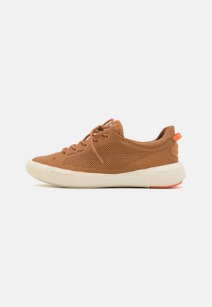 Baskets perforées marron avec une semelle texturée, dotées de lacets plats et d'un petit accent orange au talon.
