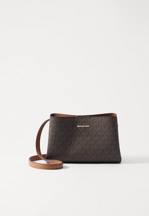 Brązowa torebka Michael Kors na ramię z regulowanym paskiem i powtarzającym się wzorem logo MK na jednolitym białym tle.