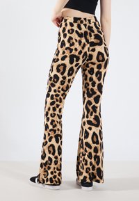 Pantalone s leopard uzorkom s potpunim krojem izrađeni od teksturirane tkanine u boji tan i crnoj, sa visokim strukom i uskim krojem kroz bokove.