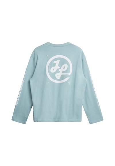 Lichtblauw overhemd met lange mouwen, met een wit cirkelvormig logo op de achterkant en tekst op de mouwen. Gemaakt van zacht katoenen materiaal.