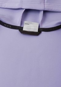 Tessuto di colore viola chiaro con una texture liscia, con un'etichetta nera con il testo "Ero qui" all'interno del collo.