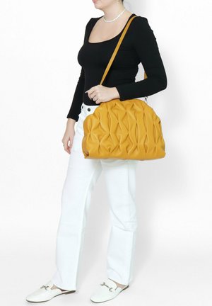 Borsa a spalla in pelle gialla con design trapuntato. Texture liscia, forma arrotondata e dettagli di cucitura visibili.