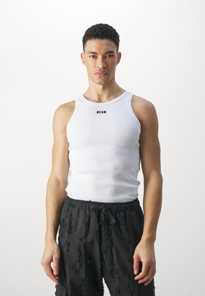 Débardeur blanc à côtes avec le logo noir "MSGM", associé à un short noir texturé. Le débardeur possède des bretelles larges et une silhouette ajustée.
