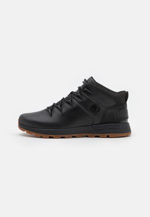 Scarpe da trekking nere in materiale sintetico, con una tomaia texture, suola in gomma e dettagli riflettenti. Tallone rinforzato e dettaglio del logo.