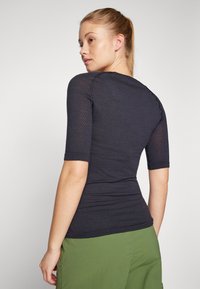 Dark blue fitted top with a textured pattern and short sleeves, paired with green cargo shorts, shown from the back.