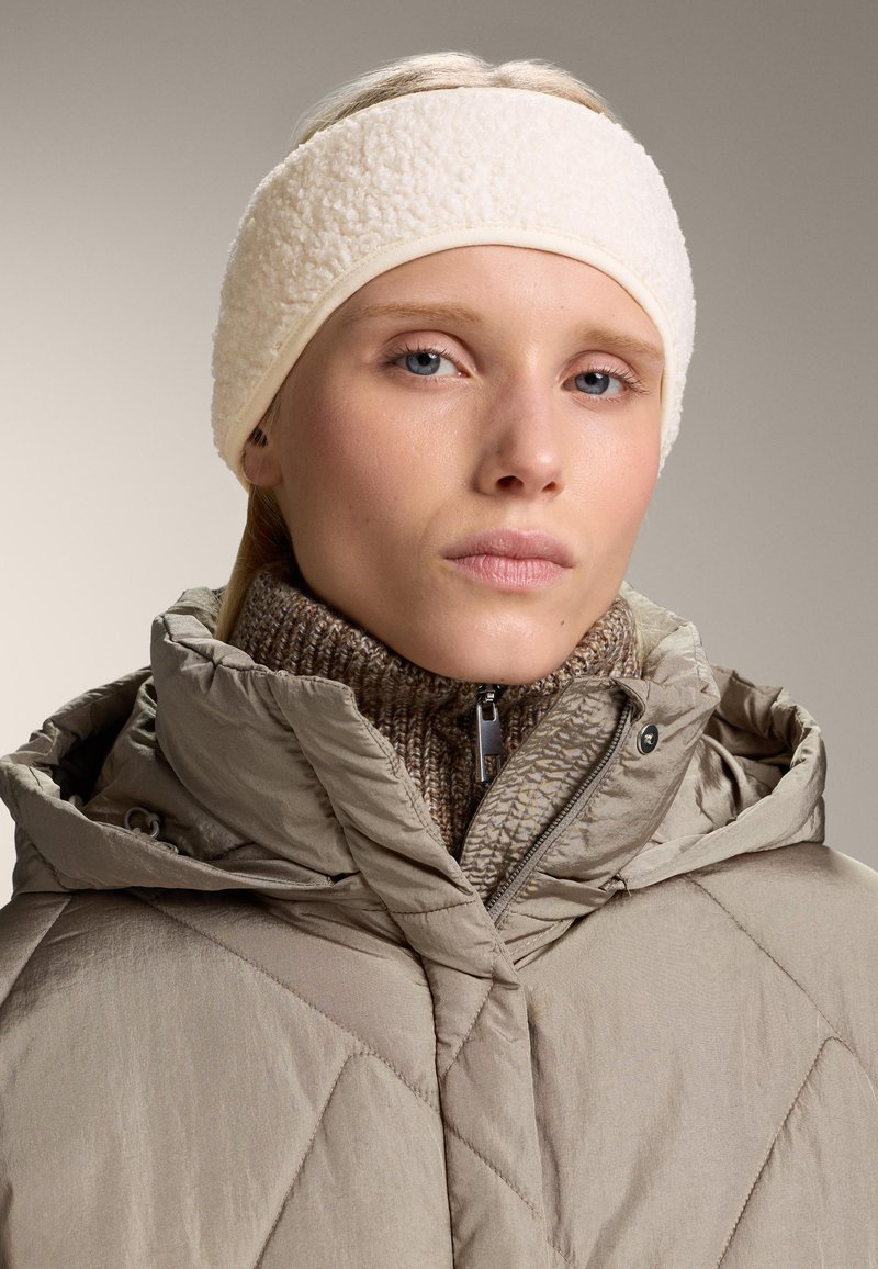 Beige vadderad jacka med hög krage och huva, ihop med ett texturerat cremefärgat fleece-pannband med släta kanter och en åtsittande passform.