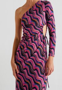 Robe asymétrique à une épaule noire avec un motif ondulé rose et violet, dotée de fronces latérales et d'un nœud accentué à la taille.