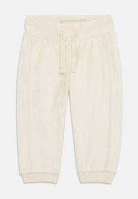 Pantalons de survêtement en velours côtelé couleur crème avec une texture côtelée, taille élastique et cordon de serrage. Des poignets ajustés au niveau de la cheville viennent compléter le design.