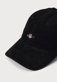 Fekete kordbársony baseball sapka hímzett logó részletekkel, ívelt karimával és texturált felülettel.