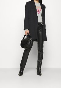 Černý tailored blejzr, šedý grafický svetr, černé kožené kalhoty a černá texturovaná kabelka. Stylové boty na jehlovém podpatku dokončují celý outfit.