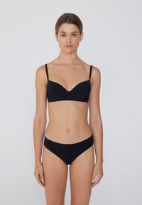 Černý bikiny set se zpevněnou, hladkou podprsenkou s kosticemi a nastavitelnými ramínky a odpovídajícími nízkými kalhotkami.