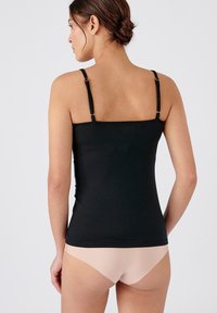 Black cotton camisole with thin straps and adjustable metal hardware, featuring a fitted design. Worn with nude-colored underwear.