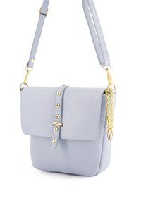 Lichtblauwe leren crossbodytas met een klep, gouden hardware en studs. Bevat een afneembare schouderriem met kettingdetail.