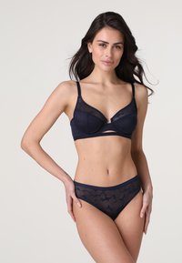 Set di lingerie blu navy con reggiseno in rete trasparente decorato con motivi floreali e un perizoma coordinato in rete trasparente con vita solida, entrambi dotati di spalline regolabili.