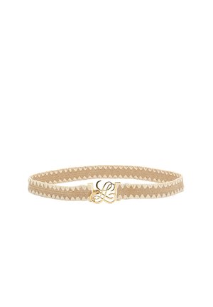 Bež tkaninski pas z belim cikcak šivom in zlatim kovinskim zaponko z motivom prepletene črke „L“.