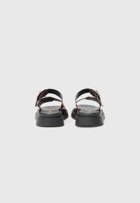 Sorte sandaler med en blank finish, med to justerbare stropper, en tykk svart såle og en subtil gullaccent på spennen.