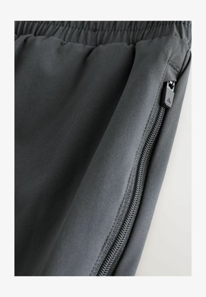 Harmaat urheilushortsit, joissa on joustava vyötärönauha, vetoketjullinen tasku ja sileä, kevyt kangas, jossa on hentoinen kiilto.