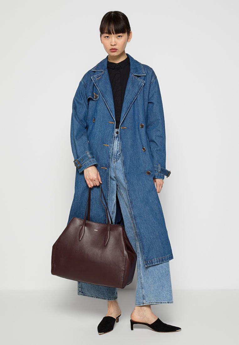 Braune Leder-Umhängetasche mit langen Griffen, schlanker rechteckiger Form, minimalistischem Design und dezenten Hardwaredetails.