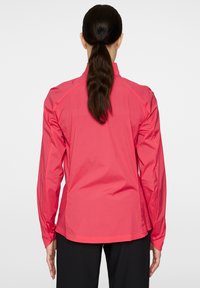 Lätt vikt, långärmad jacka i livfull rosa. Tillverkad av ett slätt, vattenavvisande material med rak passform och elastiska muddar.