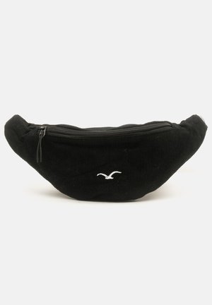 Schwarze Corduroy-Bauchtasche mit runder Form, Reißverschluss oben und einem kleinen weißen Vogel-Logo auf der Vorderseite.