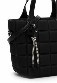 Black tote bag made of padded material, featuring a checkered design, smooth texture, dual handles, and an adjustable strap with a decorative tassel.