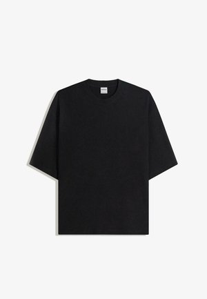 Črna over-sized majica s kratkimi rokavi in okroglim izrezom, položena na ravno površino na belem ozadju, viden je etiketa Bershka znotraj ovratnika.