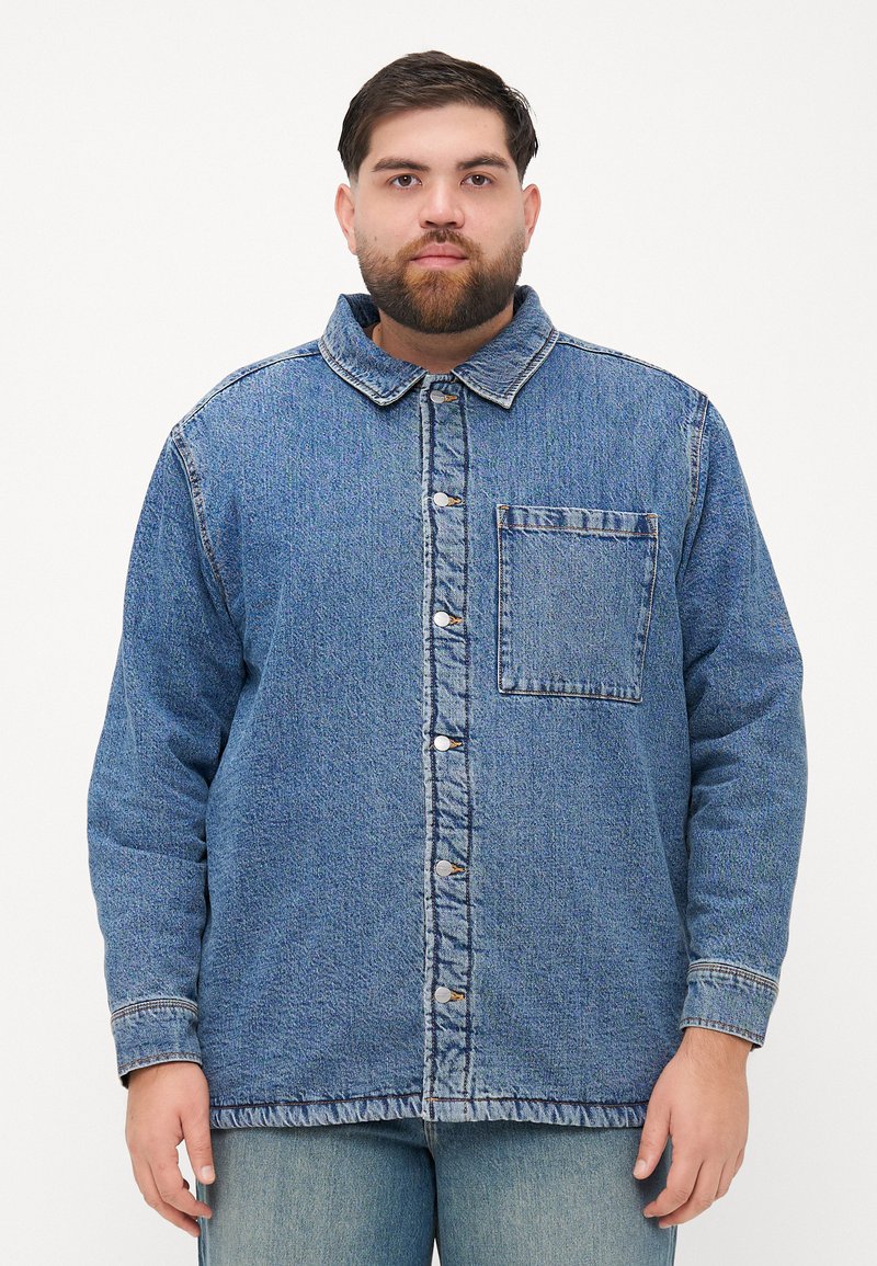 Denimhemd, blaue Farbe, Knopfdesign mit Kragen, Fronttasche und sichtbaren Nähten. Weicher Stoff und lockere Passform.