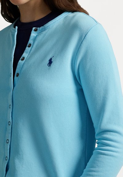 Hellblauer Cardigan mit Rundhalsausschnitt, langen Ärmeln und Knopfverschluss. Mit kleinem dunkelblauen Logo auf der Brust. Strukturierter Stoff.