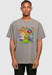 Camiseta gris de gran tamaño, confeccionada en algodón, con un gráfico colorido de cinco personajes de dibujos animados en la parte delantera. Manga corta y cuello redondo.