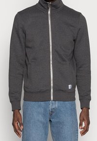 Felpa grigia con zip realizzata in cotone morbido, con colletto alto. Presenta una zip argentata, tasche laterali e polsini e orlo a coste.