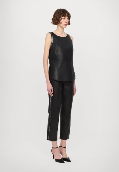 Black leather sleeveless top with rounded neckline, paired with tailored black leather pants featuring studded side accents and pointed heels.