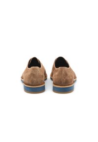 Scarpe in suede marrone con tacco curvo, suola in gomma blu a contrasto e dettagli in pelle marrone lungo il bordo della suola.