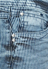 Jeans w paski denimowe w niebieskie i białe pionowe linie, z małą przednią kieszonką i trzema metalowymi guzikami na pasku.