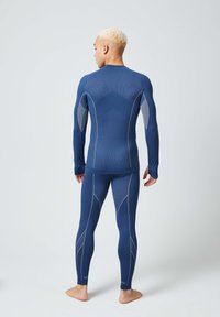 Top ajustado de manga larga azul marino y leggings, con tejido texturizado y costuras en contraste, así como acentos de malla en las mangas, acabado suave.