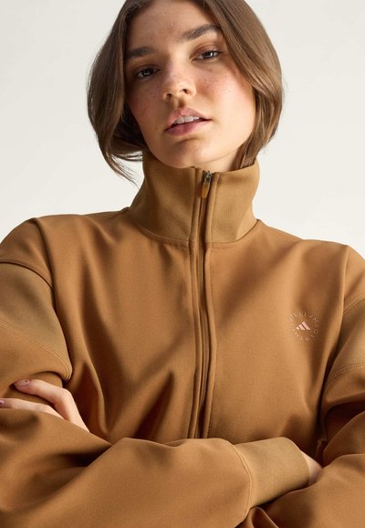 Brauner Reißverschluss-Pullover mit hohem Kragen, ausgestattet mit einem Logo auf der Brust. Weiche Textur mit kontrastierenden Ärmeldetails.