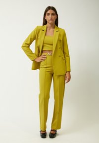 Geel blazer en bijpassende fitted broek, gemaakt van op maat gemaakt stof, met een dubbele knoopsdesign en een gouden kettingriem accent.