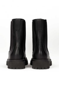 Black leather ankle boots with a textured surface, featuring a chunky rubber sole and pull tabs for easy wear.