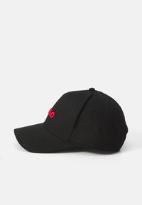 Svart baseballcaps med buet skjerm, med røde broderte bokstaver foran. Laget av stoff med en teksturert overflate.
