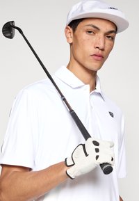 Chemise de golf blanche avec col et logo, casquette blanche et gant blanc. Club de golf noir avec tête ronde et poignée texturée.