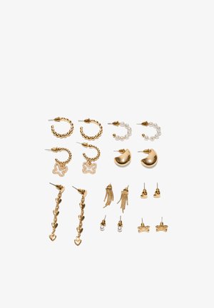 Neun Paar goldfarbene und perlenbesetzte Ohrstecker und Creolen, in Reihen auf weißem Hintergrund angeordnet, mit Herz-, Schmetterlings- und Quastenmotiven.
