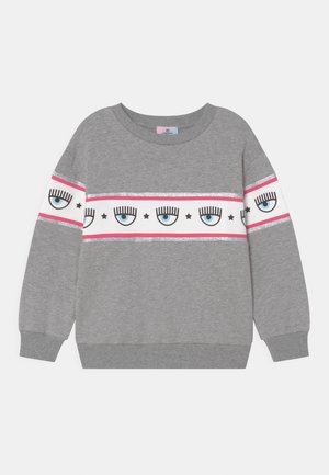Sweat-shirt gris en matière douce, orné d'une bande blanche avec des yeux bleus, des cils noirs, des accents roses et des rayures pailletées argentées.