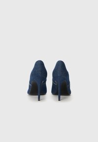 Chaussures à talons hauts en denim avec un bout pointu et un design épuré. Présentent une texture lisse et un talon aiguille. Couleur : bleu foncé.