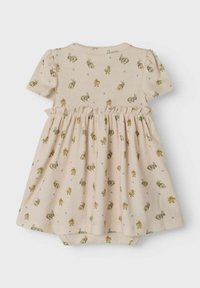 Robe rose clair à manches courtes, présentant une taille froncée. Ornées de petits lapins et poussins, fabriquée en tissu côtelé doux.