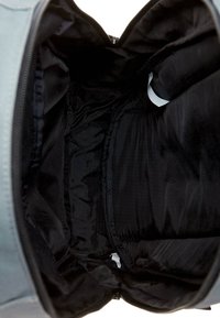 Grauer Rucksack Innenraum mit glattem schwarzen Futter, Reißverschluss und mehreren Fächern zur Organisation. Strukturierter Stoff ist sichtbar.