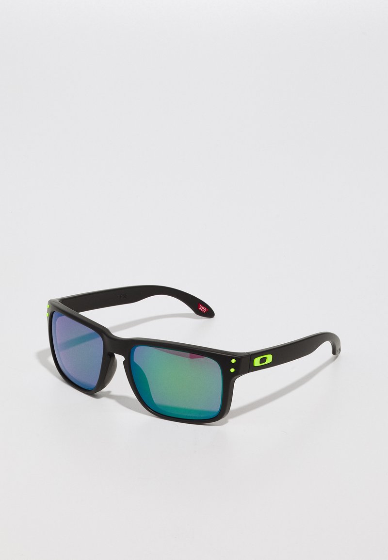 Black sunglasses with mirrored green lenses, square frame design, matte finish, and small green accents on the temples.