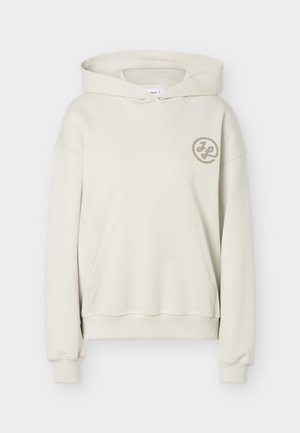 Εκρού φούτερ με κουκούλα, τσέπη καγκουρό και μικρό κυκλικό λογότυπο στο αριστερό στήθος, εμφανίζεται μπροστά σε απλό φόντο.